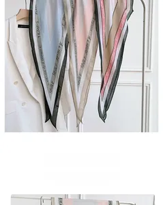 Detail of diamond-shaped silk scarf with artistic typography and black hemmed edges