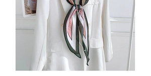 Close-up of elegant tricolor silk scarf tied on a white blazer with French retro style