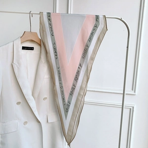 Minimalist geometric V-pattern silk scarf in pink and grey hanging on a wooden hanger