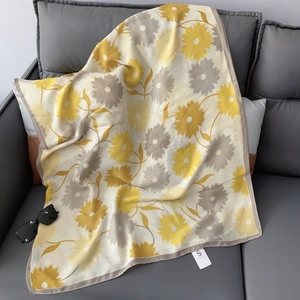 Close-up of floral print scarf in yellow and grey on soft beige cotton linen fabric
