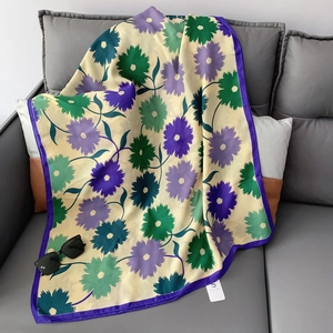Detail of floral linen-cotton scarf with purple border draped on a grey sofa