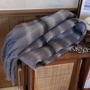 Détail d'une écharpe moelleuse à rayures bleu et gris avec de longues franges