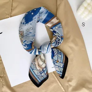 Detailed close-up of blue silk scarf with cat and star patterns on neutral background