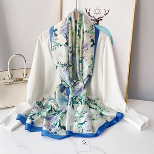 Detail of silk-feel scarf with blue floral print and elegant drape over white shirt