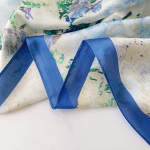Detailed view of the soft silk scarf with watercolor floral patterns and dark blue border