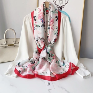 Floral print silk scarf with red borders draped over a white shirt for a stylish look