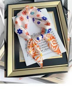 Close-up of pink silk scarf with floral daisy patterns draped on a gold frame