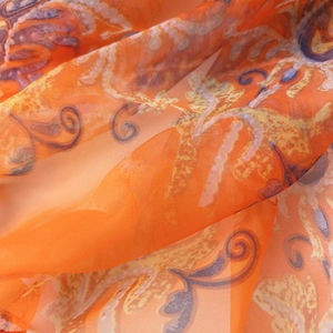 Close-up of lightweight orange chiffon scarf with intricate paisley patterns and soft texture