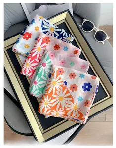 Colorful daisy printed silk scarves stacked with sunglasses for stylish decoration