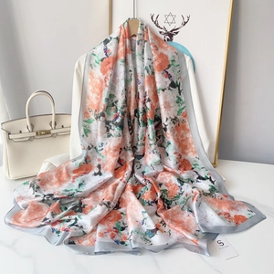 Elegant long silk scarf with orange and green floral print on white top display