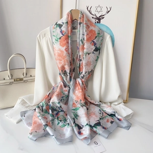 Detailed view of lightweight floral silk scarf draped over a white shirt with orange accents