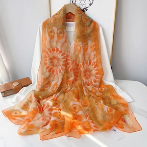 Detail of vibrant orange floral chiffon scarf draped elegantly over a wooden hanger