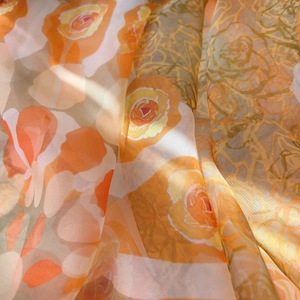 Close-up of orange rose floral chiffon fabric showing translucent texture and soft light
