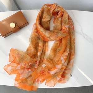 Detailed macro view of orange rose print silk scarf texture and fine hemmed edges