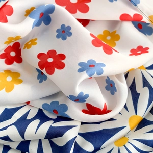 Detailed view of colorful daisy print on smooth satin fabric with elegant drape