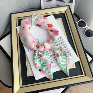 Close-up of pink silk scarf with floral daisy prints and elegant glossy texture