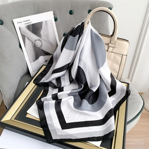 Close-up of geometric silk scarf tied to a beige handbag with artistic minimalist decor