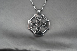 Gros plan du pendentif croix celtique avec motifs entrelacés sur fond en satin noir