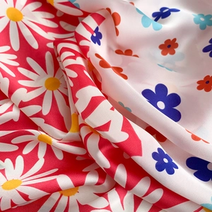 Close-up of smooth silk satin scarf fabric showing daisy floral print and glossy texture