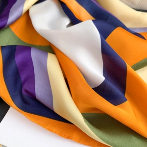 Detailed macro view of vibrant geometric silk scarf with professional hemmed edges