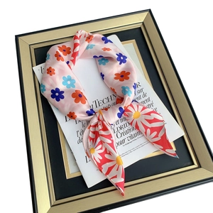 Pink silk-like square scarf with vibrant daisy floral print and elegant bowtie styling
