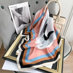 Silk-like geometric print square scarf in pink and blue styled on a beige handbag
