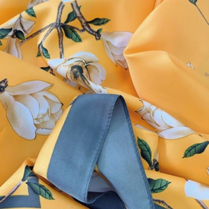 Macro shot of silk floral scarf showing yellow fabric texture and white magnolia print