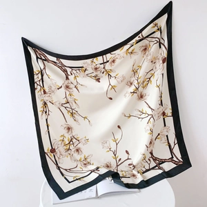 Artistic drape of a beige silk scarf with black borders and elegant magnolia flower patterns