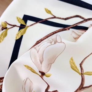 Detail of silk-like scarf featuring elegant magnolia floral prints and smooth satin texture