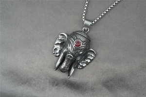Macro detail of elephant pendant with red gemstone and vintage silver texture finish