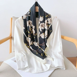 Detail of silk-like scarf with white magnolia flowers draped over a white blouse