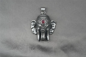 Detail of vintage Ganesha pendant in stainless steel with a red stone and ornate carvings