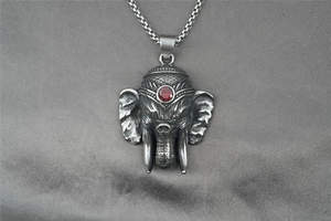 Macro detail of vintage elephant god pendant in titanium steel with red gemstone