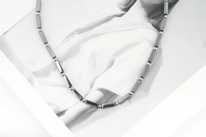 Close-up of minimalist titanium steel necklace with dark grey beads and silver spheres