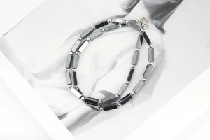 Detail of hematite beaded necklace featuring dark metallic beads on magazine background