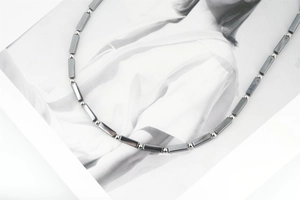 Detail of beaded titanium steel necklace with grey hematite blocks and silver round beads