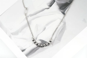 Detail of silver Cuban chain necklace with square metal beads on a fashion magazine background