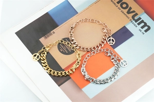 Detailed macro of gold and silver Cuban link bracelets featuring a peace sign pendant