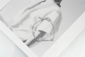 Detailed macro view of silver daisy charm bracelet with polished metal beads and lobster clasp