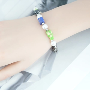 Bracelet bohème avec perles blanches et pierres vertes porté sur le poignet d'un mannequin