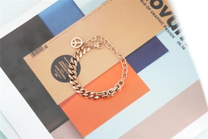 Detail of rose gold Cuban link bracelet with square links and peace sign charm