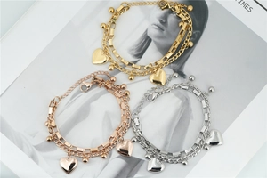 Detailed view of double-layer stainless steel bracelet with heart charms in gold finish