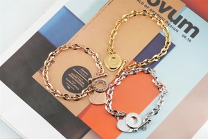 Detailed view of three-tone OT buckle bracelets with Bible verse heart charms on a magazine
