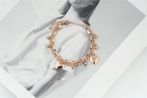 Detailed macro of rose gold double-layer chain bracelet with a 3D heart charm