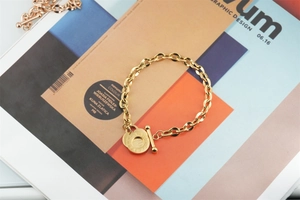 Detail of gold chain bracelet with OT toggle clasp and dual circular coin charms