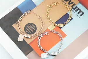 Detailed shot of triple-colored titanium steel bracelet with Good Luck tag and lobster clasp