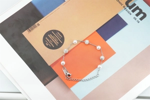 Détail du bracelet en acier inoxydable argenté avec cinq perles blanches et trois billes