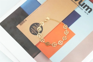 Gros plan d'un bracelet Arbre de Vie doré en acier titane sur un magazine de mode