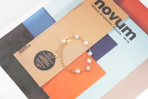 Détail d'un élégant bracelet en or avec perles et boules pavées sur un magazine