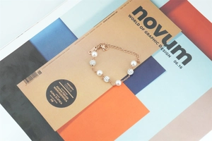 Détail d'un bracelet en perles d'or rose avec sphères en cristal sur un magazine d'art